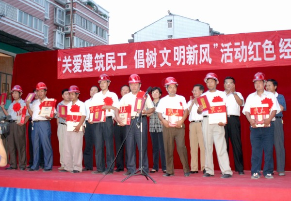 8名建筑民工代表胸佩红花走向领奖台，从市领导手中接过获奖证书